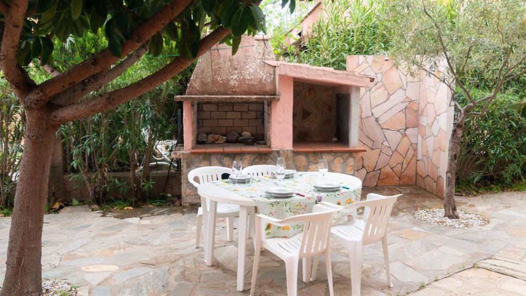 uma mesa branca e cadeiras com um forno de tijolos em Casa Ficus em Porto Ottiolu