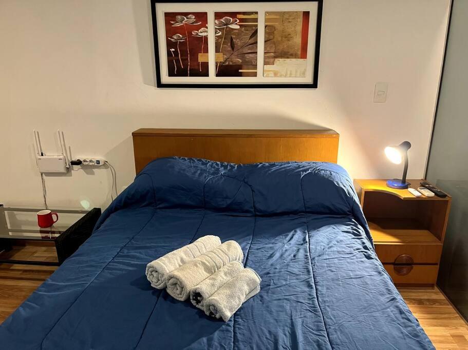 Una cama con sábanas azules y dos toallas. en Apartamento Studio cerca Pocitos, en Montevideo