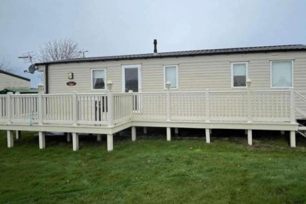 a house with a porch and a white fence at Sunshine caravans in Eastchurch