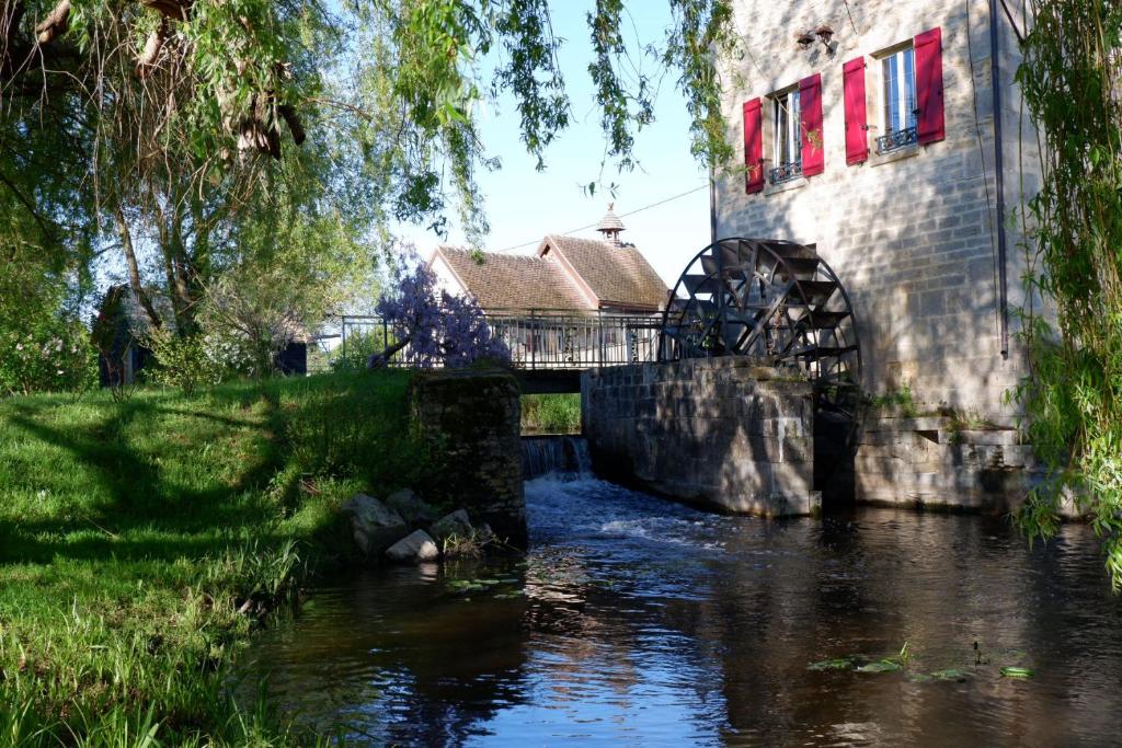 eine Brücke über einen Fluss neben einem Gebäude in der Unterkunft Moulin de Petoulle in Charenton sur Cher