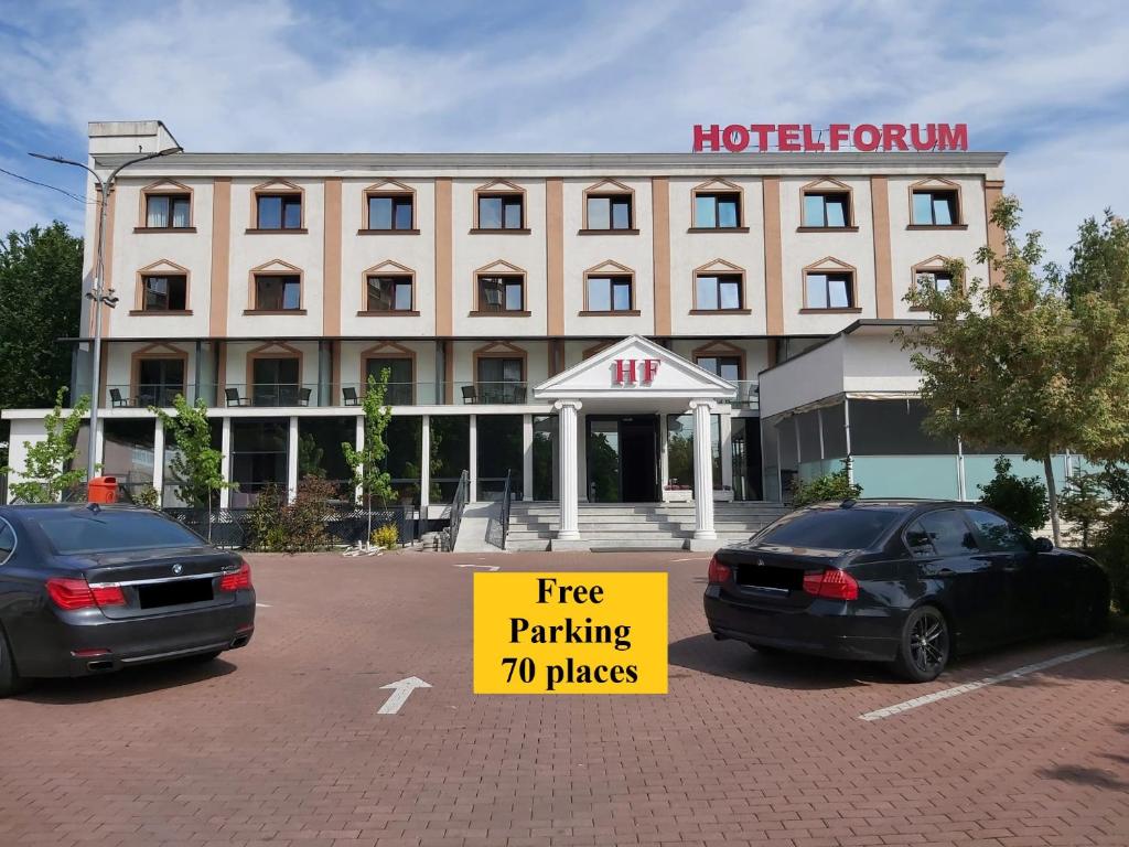 dwa samochody zaparkowane na parkingu przed hotelem w obiekcie Hotel Forum w mieście Ploeszti