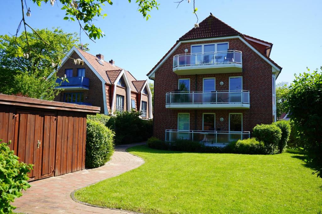 a brick house with a fence and a yard at Kurpark Domizil 2 in Cuxhaven