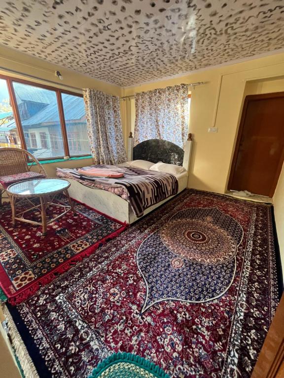 a bedroom with a bed and a table and a rug at Pine Brooke Pahalgam in Pahalgām