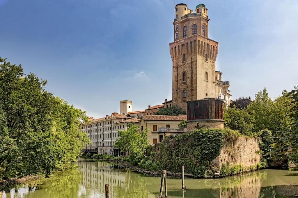 um edifício com uma torre de relógio ao lado de um rio em Locanda Munerato em Pádua