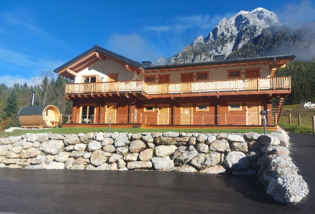 une grande cabane en rondins avec un mur en pierre à l'avant dans l'établissement Xeis Natur Apartments, à Johnsbach