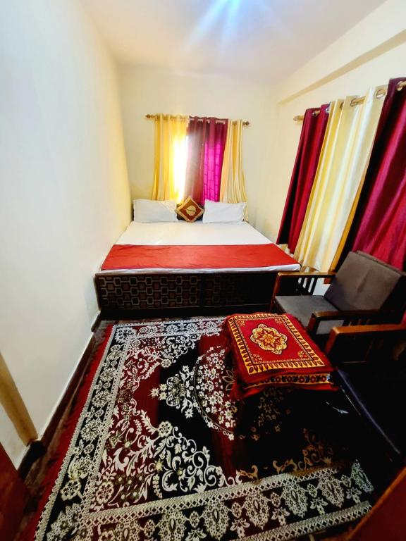 a bedroom with a bed with red curtains and a rug at Snow land cottage in Manāli
