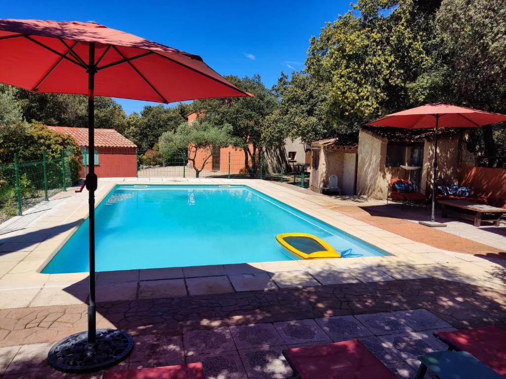 une piscine avec un parasol rouge et une chaise jaune dans l'établissement Villa Dervonnae, la Provence à l'ombre des Chênes, à Tavernes
