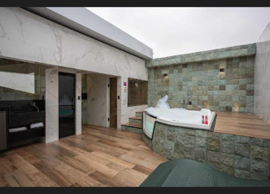 Motel Desireé في ساو باولو: حمام كبير مع حوض استحمام وجدار حجري