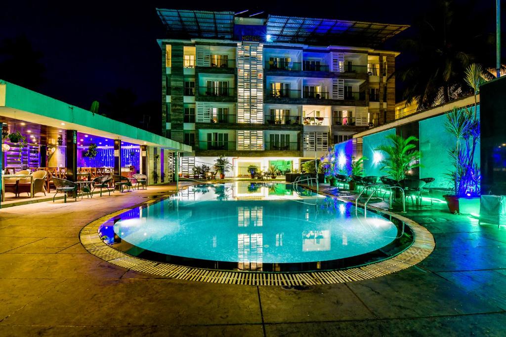 a swimming pool in front of a building at night at FabHotel Prime The King's Court Calangute with Pool and Bar in Calangute