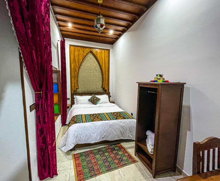 a small bedroom with a bed and a red curtain at Riad el wazzania in Rabat
