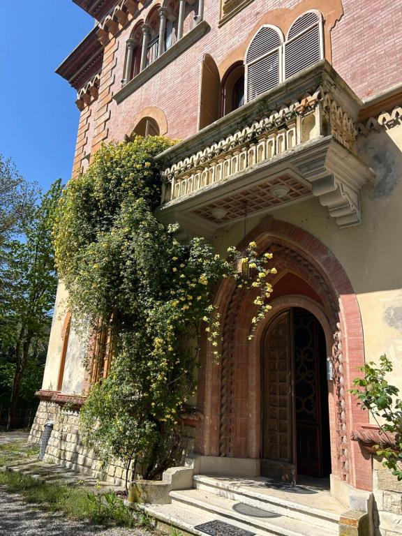 un grand bâtiment en briques avec une porte et une brousse dans l'établissement Villa Tirotti, à Plaisance