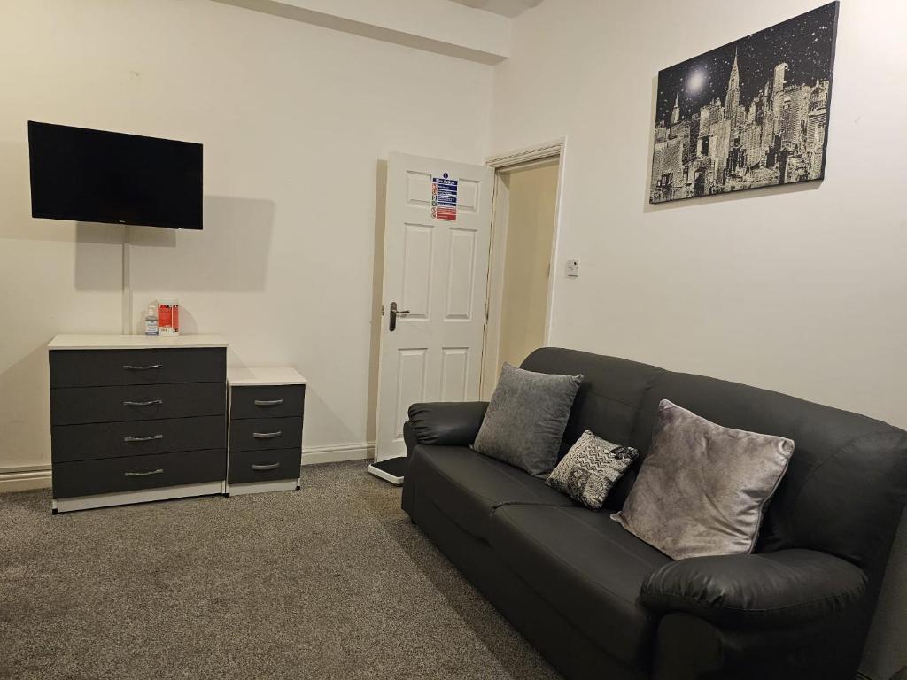 un soggiorno con divano nero e cassettiera di Hygis Great Home of Relaxations a Stoke on Trent