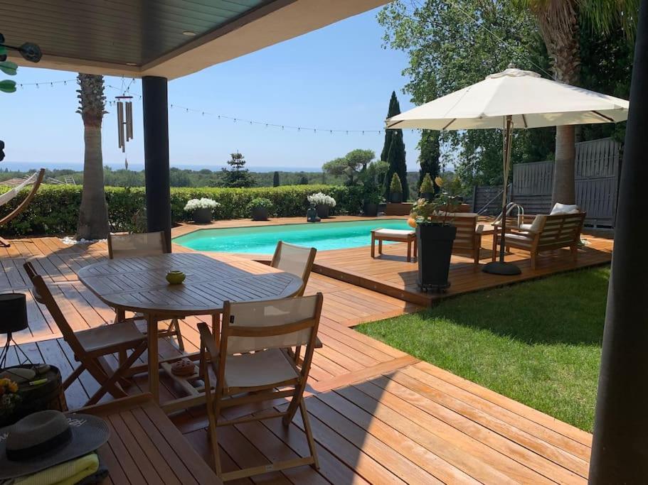 une terrasse en bois avec une table, des chaises et un parasol dans l'établissement Villa Azur - Sea View, à Villeneuve-Loubet