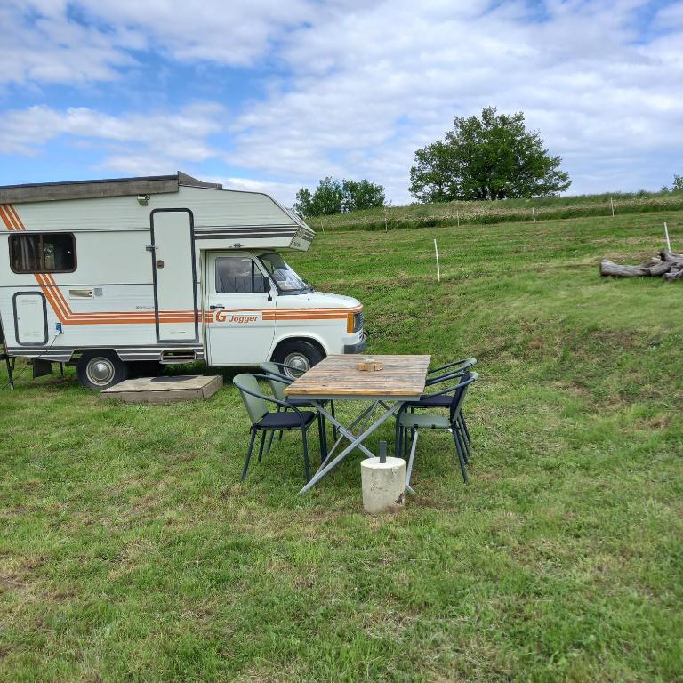 uma mesa e cadeiras em frente a uma caravana em Camping car vintage em Saint-Barthélemy-le-Plain