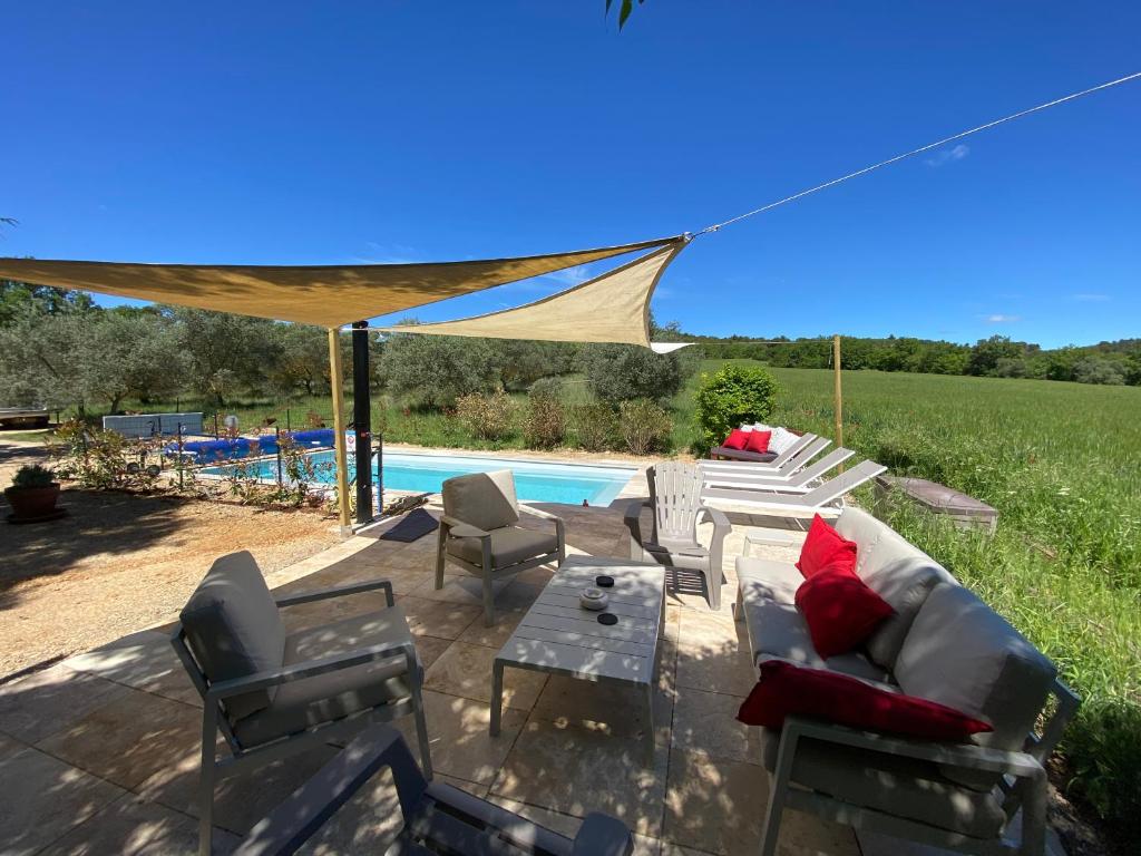 un patio con sofá y sillas junto a la piscina en La Colombiere du Château, en Saint-Laurent-du-Verdon