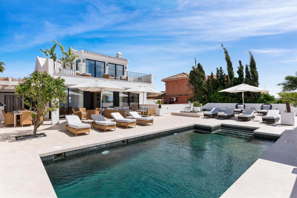 a house with a swimming pool and patio with chairs and umbrellas at 20600 - Luxurious Beachside Villa Near Marbella in Marbella