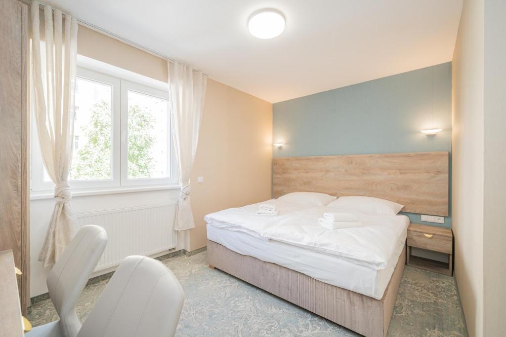 a bedroom with a bed and a desk and a window at Rabie Aparthotel in Prague