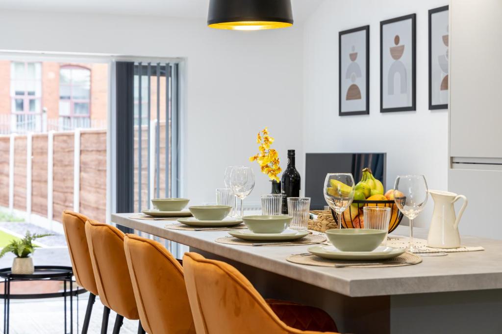 a dining room with a table with chairs and wine glasses at Spacious & Modern 4-Bedroom Townhouse in Manchester