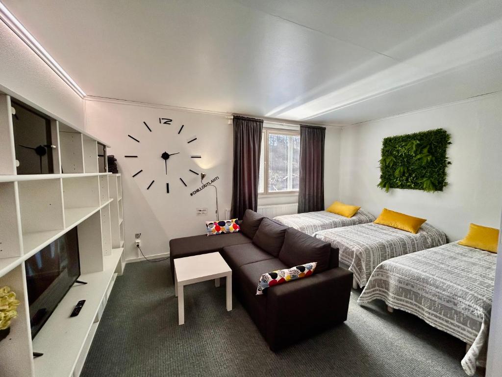 a living room with a couch and a clock on the wall at ChillOut Studio Apartment Lahti in Lahti