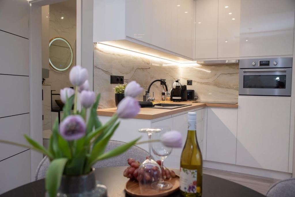 凱斯特海伊的住宿－Marina Luxury Aparment，厨房配有一瓶葡萄酒和一瓶鲜花
