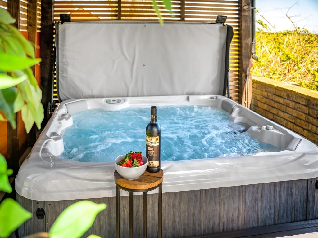 a hot tub with a bottle of wine and a bowl of strawberries at Valhallah Cottage Retreat in Broomhill