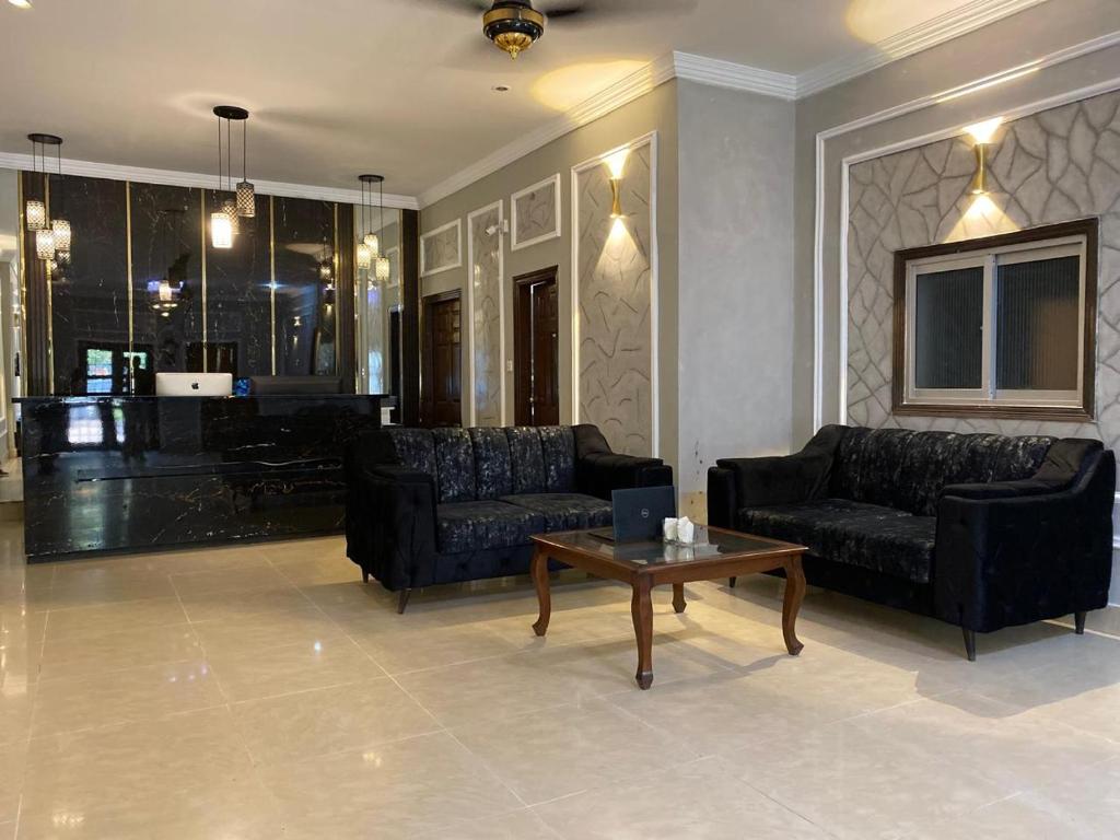 ein Wohnzimmer mit zwei schwarzen Sofas und einem Couchtisch in der Unterkunft Rehmat Residency Guest House in Islamabad