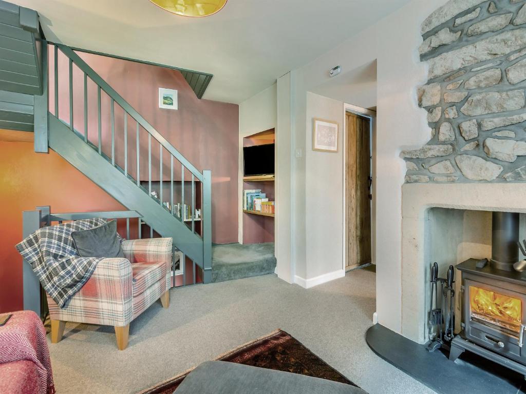 a living room with a fireplace and a staircase at Castlebergh Cottage in Settle