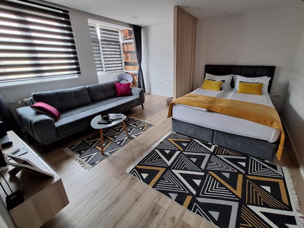 a bedroom with a bed and a couch at Apartman Orhideja with Free Parking in Sarajevo