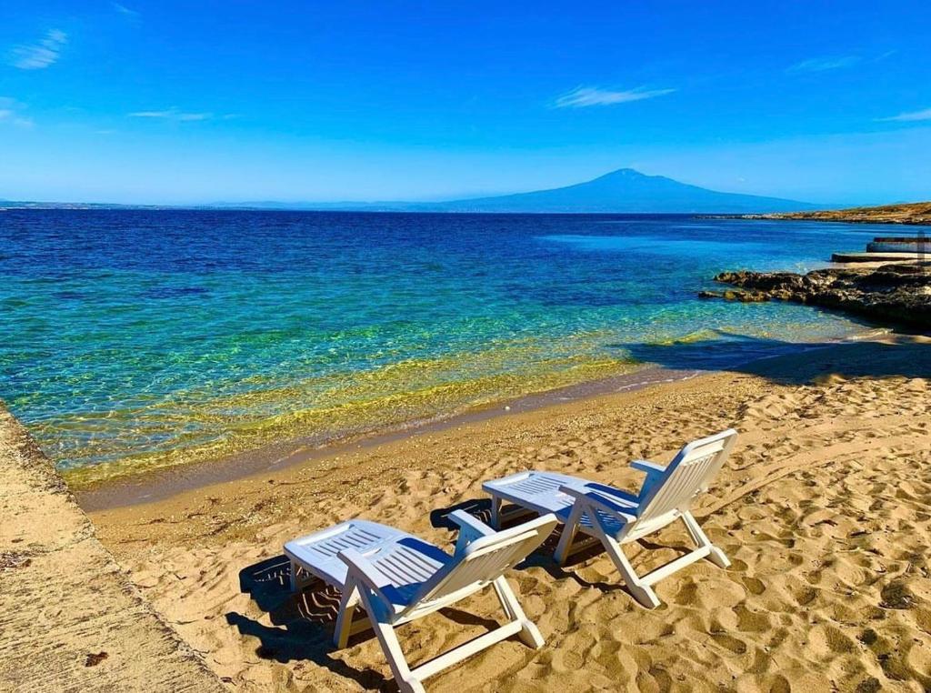 twee ligstoelen op een strand bij het water bij Blue Sea villa in Brucoli