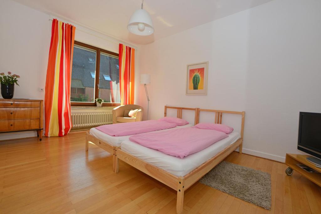 Moderne Ferienwohnung Deichstrasse في هيننف: غرفة نوم بسرير وردي وتلفزيون