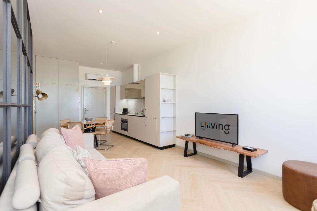 ein Wohnzimmer mit einem weißen Sofa und einem TV in der Unterkunft Liiiving in Porto - Foz Seaside Design in Porto