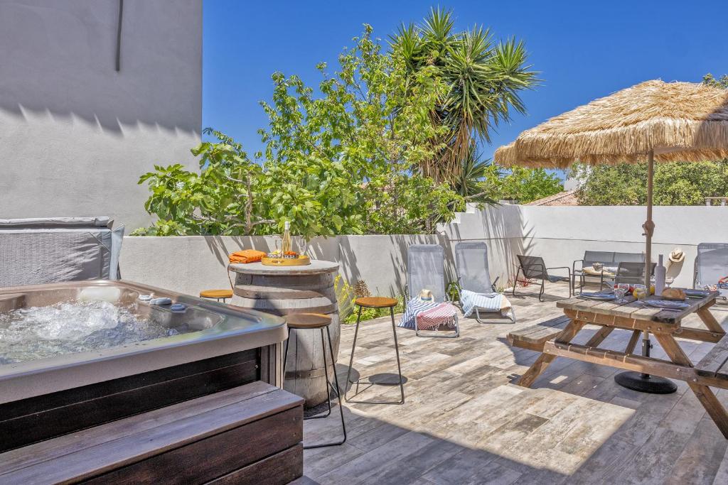 une terrasse avec un bain à remous, des tables et un parasol dans l'établissement E Case Olivia Casa 2, à Monticello