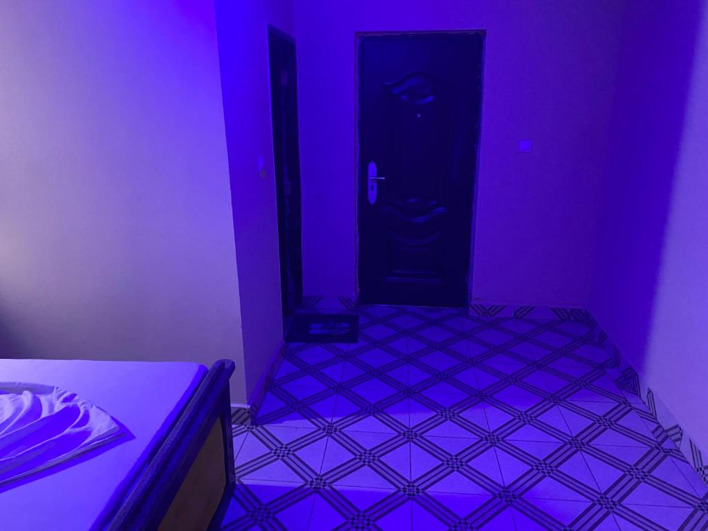 Habitación de color púrpura con cama y puerta en House Of Lottie, en Garoua