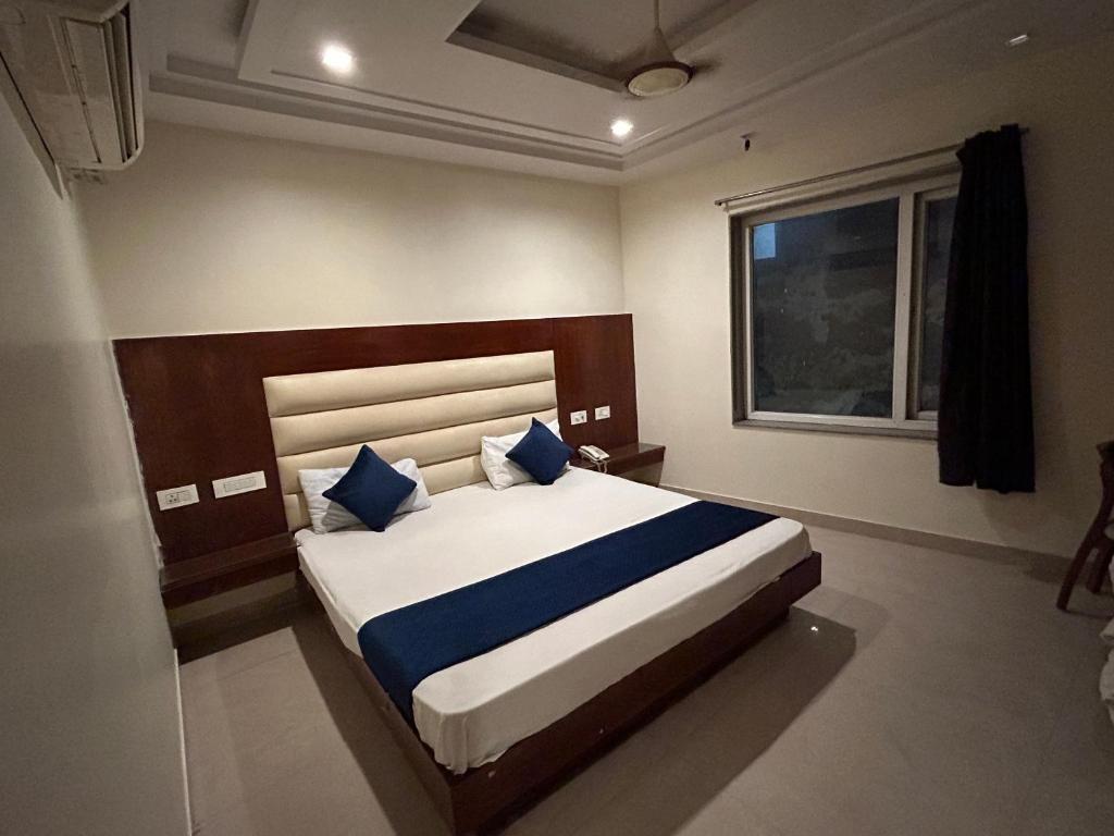 a bedroom with a bed with blue pillows and a window at Hotel Sapphire At New Delhi Railway Station in New Delhi