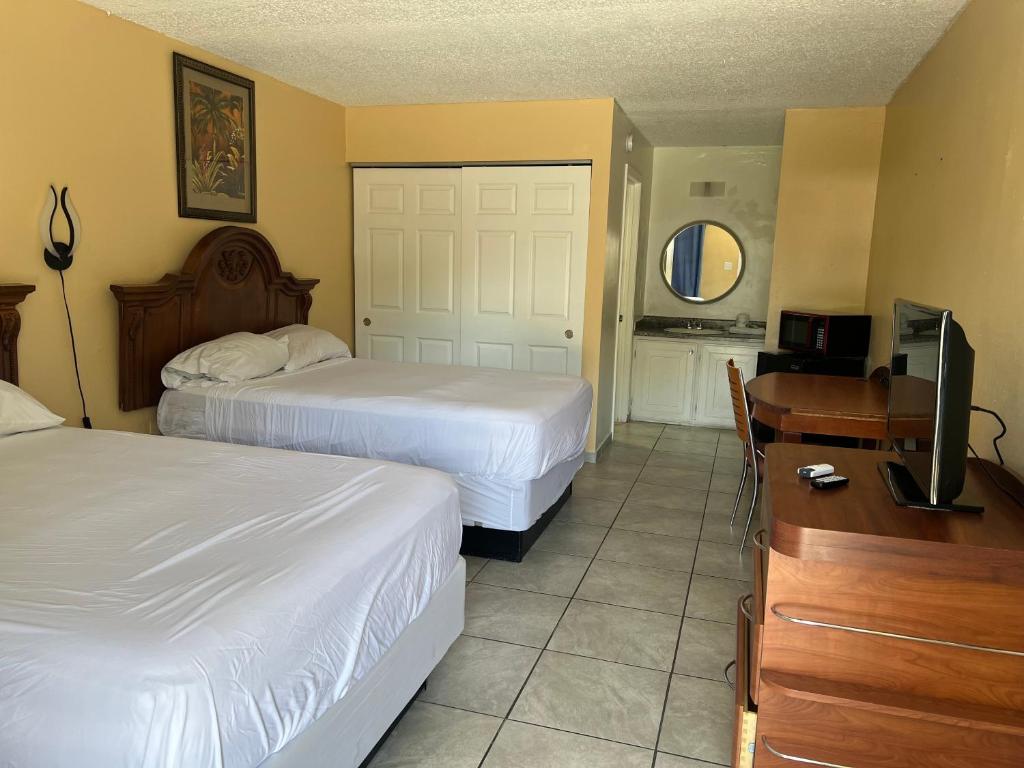 a hotel room with two beds and a desk and a television at ParadiseInn in Kissimmee