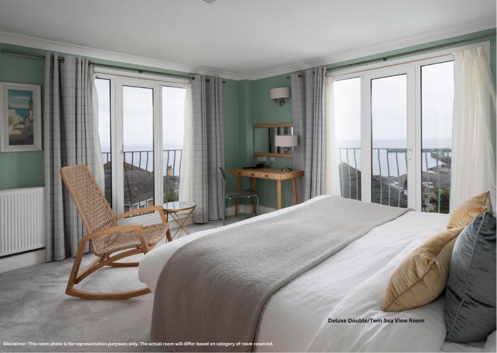 a bedroom with a bed and a chair and windows at Hotel Penzance in Penzance