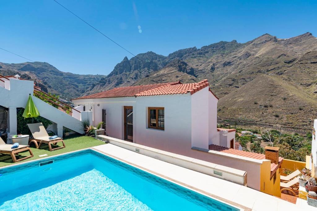 uma villa com piscina e montanhas ao fundo em Las Mimosas em Agaete