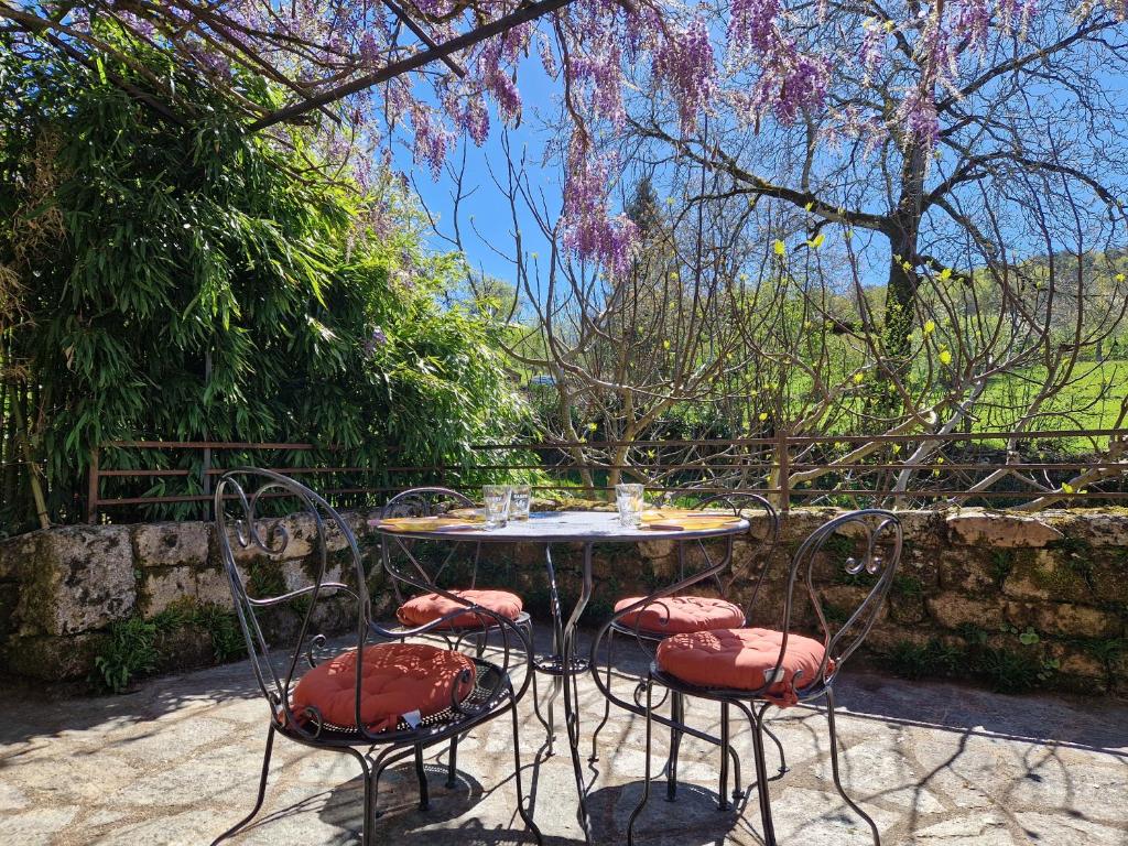 una mesa con cuatro sillas y un árbol con flores rosas en La Fontaine d'Aubrac, en Florentin-la-Capelle