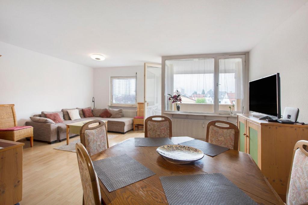 a living room with a dining room table and a television at Stadtappartement Sievers in Weil am Rhein