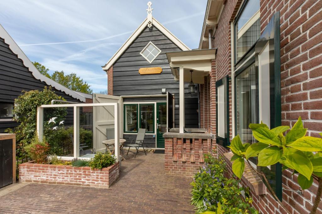 een stenen huis met een patio en ramen bij Vakantiehuis - Middelburgsestraat 61a - Koudekerke 'Villa Querina' in Koudekerke