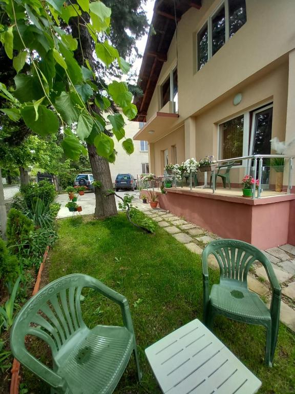- deux chaises vertes et une table en face d'une maison dans l'établissement Стаи за гости - Цветето на Ангела, à Bankya
