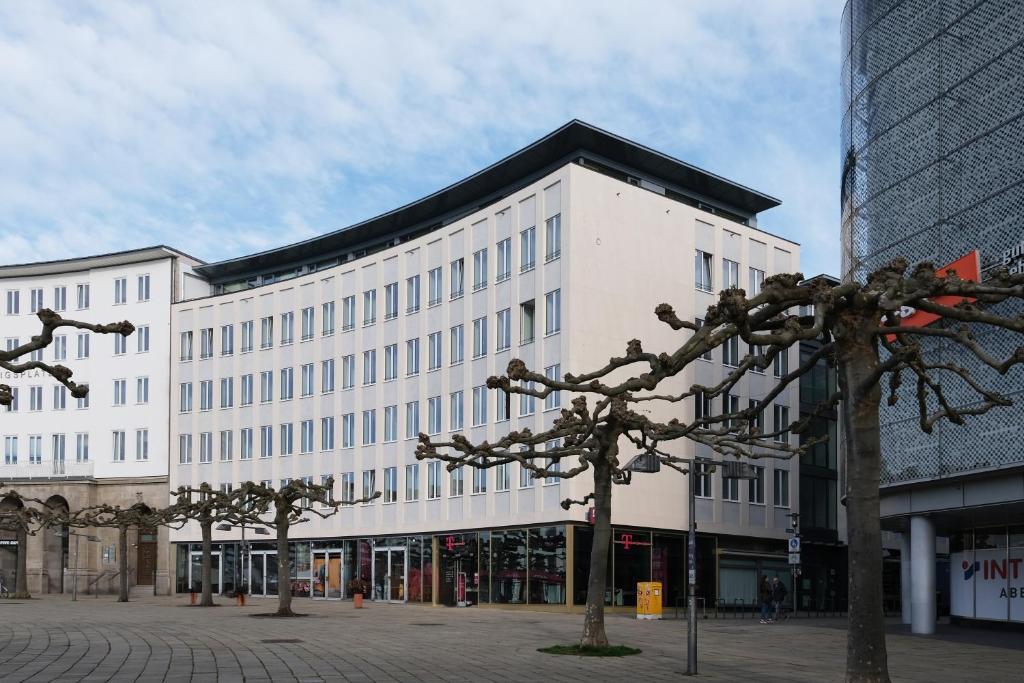 een groot wit gebouw met bomen ervoor bij Hood House Kassel in Kassel