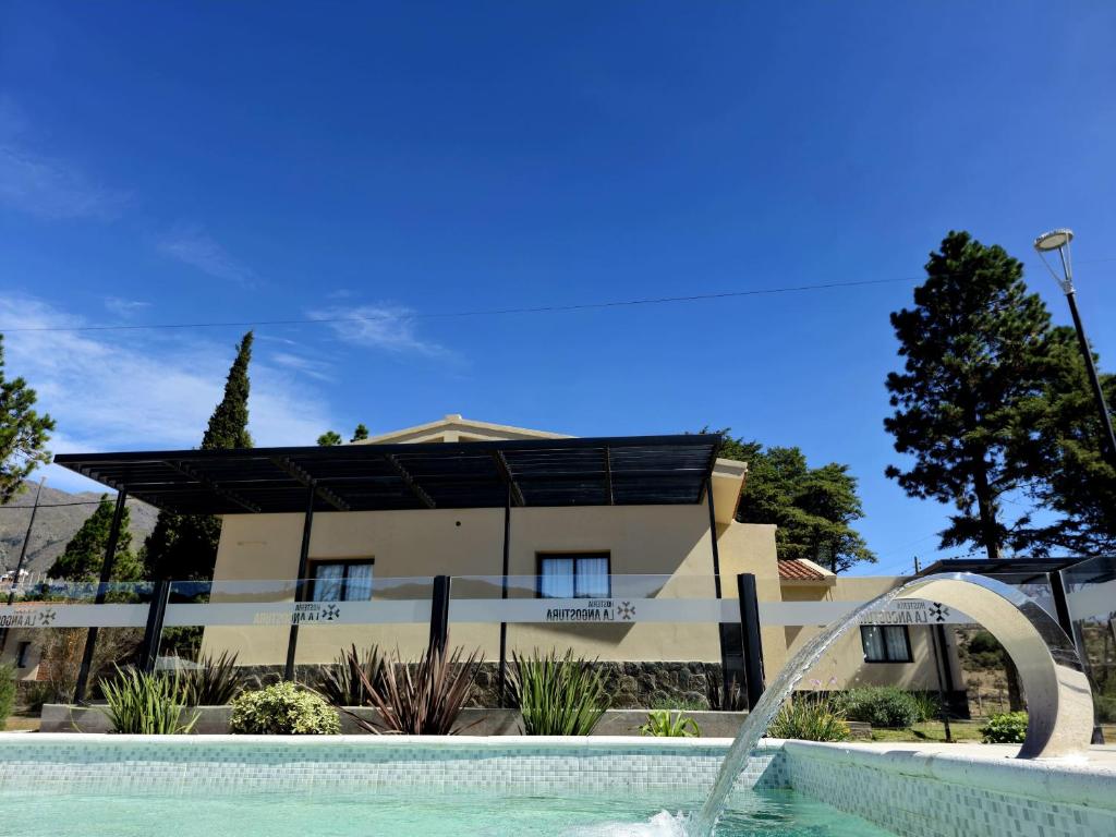 uma piscina em frente a um edifício com uma casa em Hostería La Angostura em Tafí del Valle