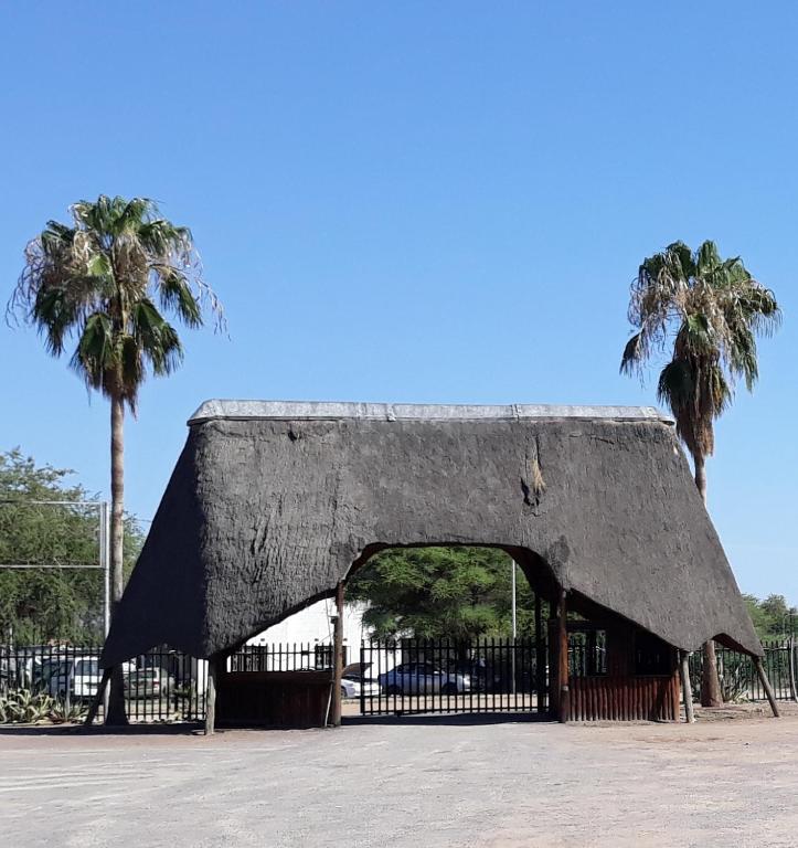 a large building with a gate and palm trees at The Big Five Lodge in Gaborone