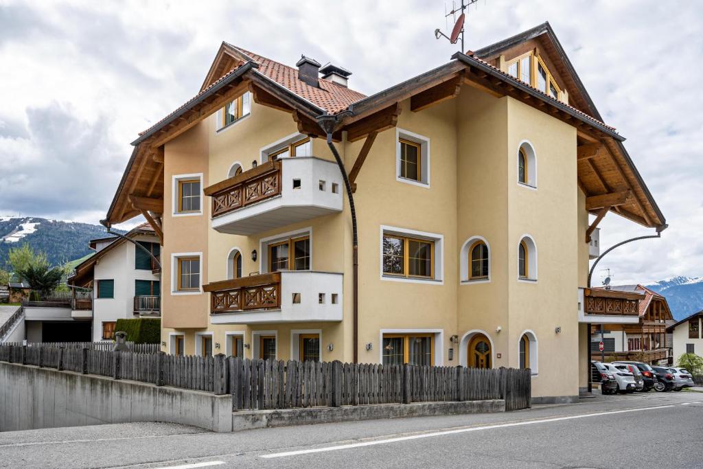 una gran casa amarilla con una valla de madera en Residence Oberhauser Apt 4 en Valdaora di Sopra