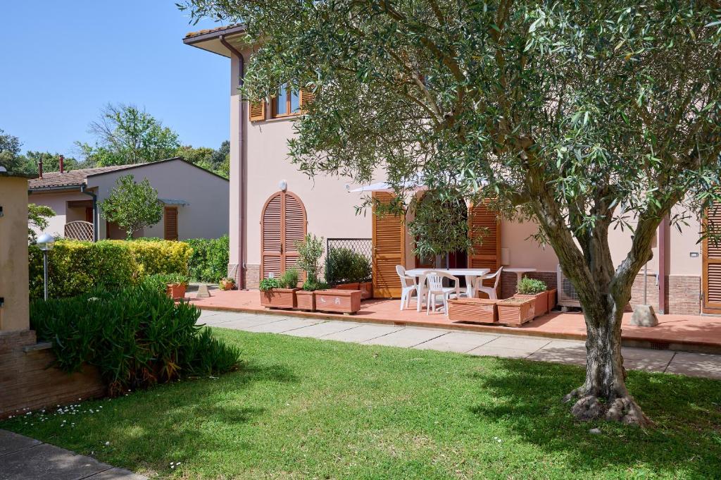 ein Haus mit einem Hof mit einem Tisch und einem Baum in der Unterkunft Trilocale San Luigi a San Vincenzo in San Vincenzo