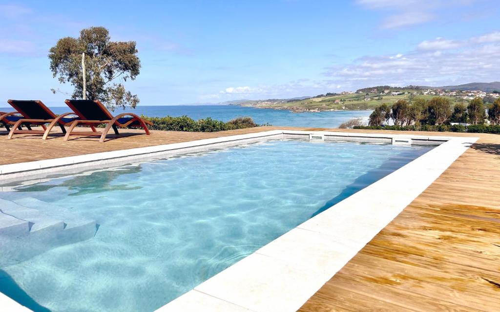 uma piscina com cadeiras e vista para o oceano em Espectacular Villa con acceso privado a la playa de Oyambre em San Vicente de la Barquera