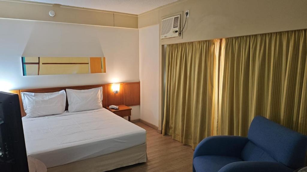 サンパウロにあるHotel Live Logde Vila Mariana Pq Ibirapuera UH-511のホテルルーム(ベッド1台、青い椅子付)