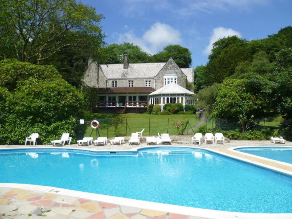 a pool with chairs and a house in the background at 3 Bedroom Lodge Lanteglos 1 in Lanteglos
