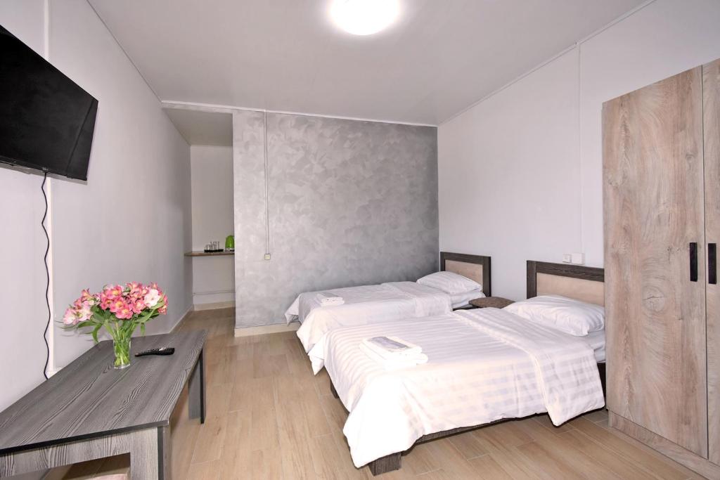 ein Schlafzimmer mit 2 Betten und einem Tisch mit Blumen in der Unterkunft Sirik in Yerevan
